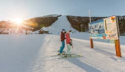 Zwei Skifahrer schauen den Pistenplan an und zeigen darauf